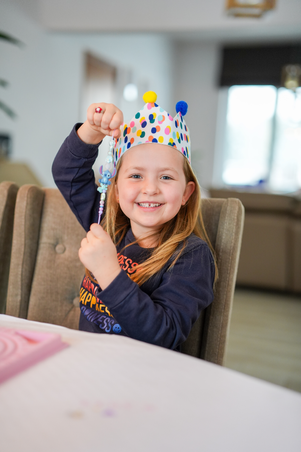 Stralend meisje met kroontje toont trots haar zelfgemaakte kralenarmbandje